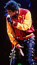 Person wearing a red and yellow jacket with a prominent letter 'M' on stage.