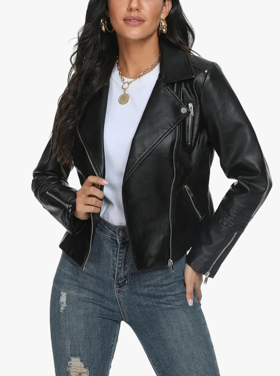 A woman wearing a black faux-leather moto jacket over a white t-shirt and distressed blue jeans, shown from the chest down against a plain white background.