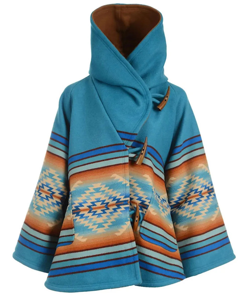 A women's wrap-style cape coat featuring a solid turquoise blue upper section and a Southwestern geometric patterned lower section in blue, orange, beige, and white. It has a high collar, a wrap-around front closure with brown toggle details, and wide sleeves, shown against a plain white background.