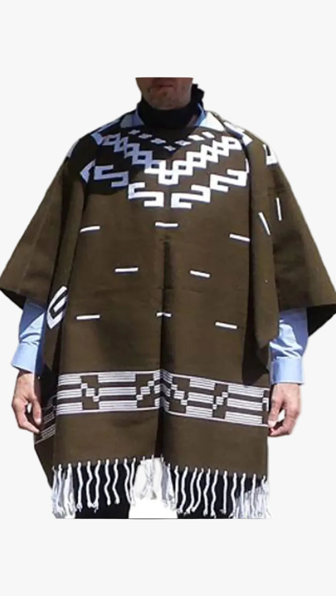 A brown woven poncho with white geometric patterns and fringe, worn over a light blue shirt and black turtleneck.