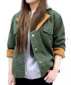 A woman wearing an olive green utility jacket with contrasting tan collar and cuff lining, layered over a light gray top.