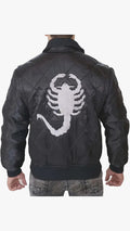 A man viewed from behind wearing a black quilted leather bomber jacket with a large white embroidered scorpion graphic on the back, paired with gray jeans against a light gray studio background.