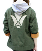 An olive green hooded jacket with a large white geometric graphic on the back, featuring tan lining on the rolled-up sleeves, shown on a model from the back.